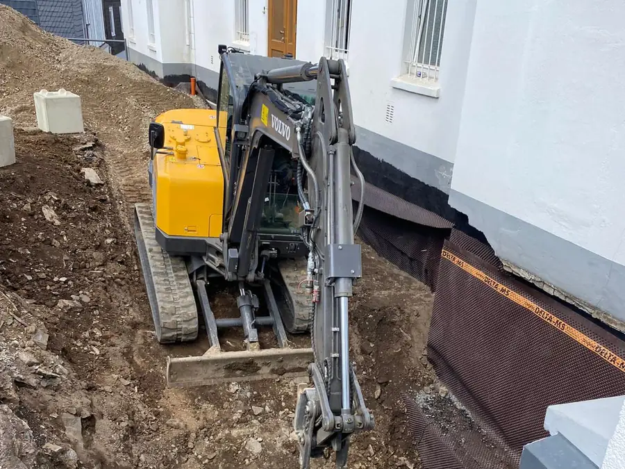 Minibagger beim Aushub einer Baugrube direkt am Haus in Siegen