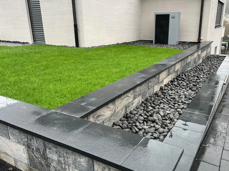 Neue Rasenfläche mit Mauer, Kiesstreifen und angrenzender Terrasse